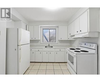 A white kitchen with a refrigerator, stove, and cabinets.