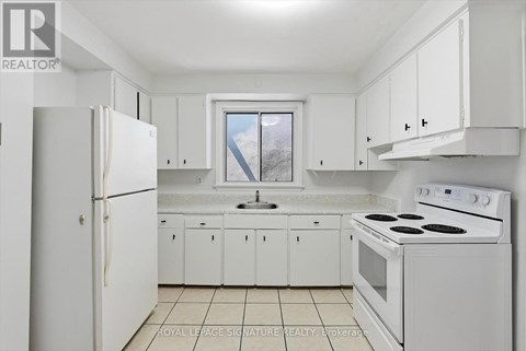 A white kitchen with a refrigerator, stove, and cabinets.