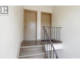 A staircase with a metal railing and wooden steps leading to a door.