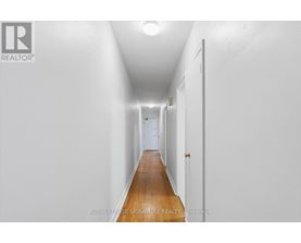 A long hallway with white walls and a wooden floor.