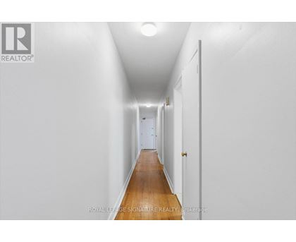 A long hallway with white walls and a wooden floor.