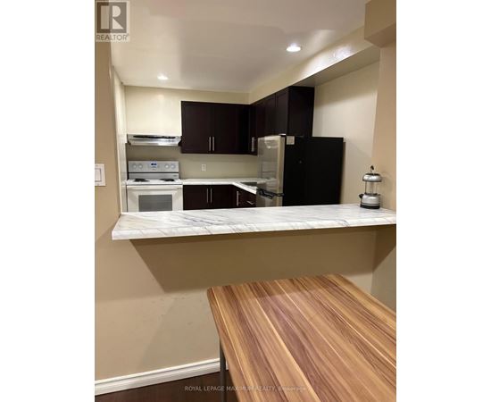 A kitchen with a black refrigerator and wooden countertop.