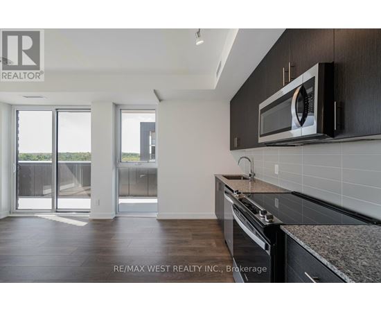A kitchen with a microwave on the wall and a stove top oven.