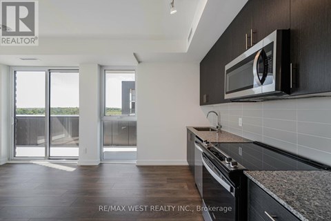 A kitchen with a microwave on the wall and a stove top oven.