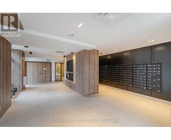 A modern office space with a long hallway and a digital display board on the wall.