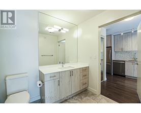 A bathroom with a toilet, sink, and mirror.
