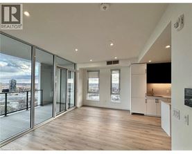 A spacious room with wooden flooring and large windows overlooking a cityscape.