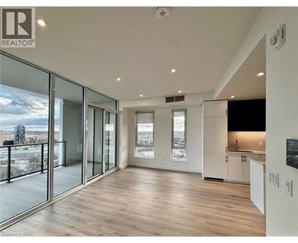 A spacious room with wooden flooring and large windows overlooking a cityscape.
