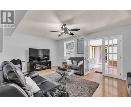 A living room with a black leather couch and a flat screen TV.