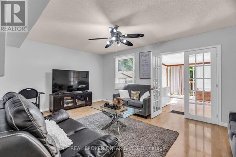 A living room with a black leather couch and a flat screen TV.