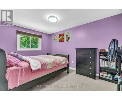 A bedroom with a pink bed and a black dresser.