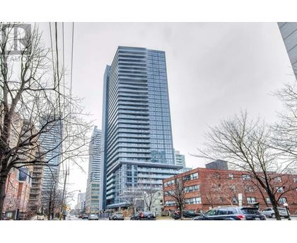 A tall glass building stands in the middle of a city street.