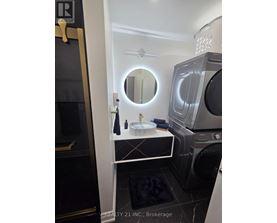 A modern bathroom with a round mirror and a washing machine built into the cabinet.