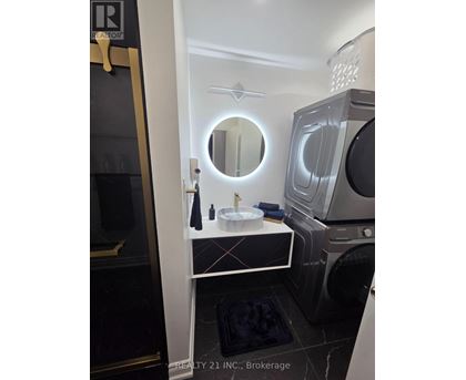 A modern bathroom with a round mirror and a washing machine built into the cabinet.
