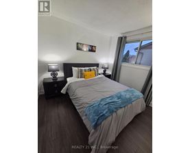 A bedroom with a bed, nightstands, and a window.