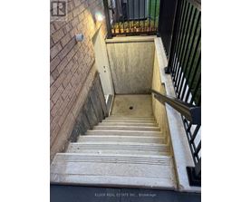 A staircase with a black railing and a brick wall.