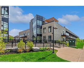 A modern building with a mix of glass and stone facades, surrounded by a well-maintained lawn and a metal fence.