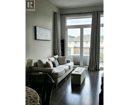 A living room with a grey couch and a painting on the wall.