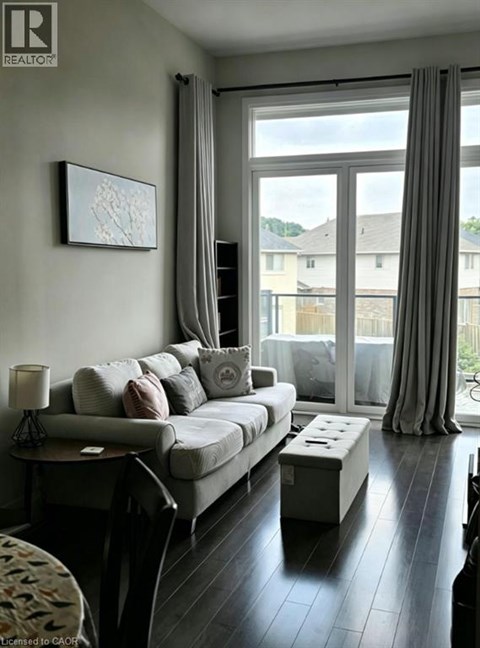 A living room with a grey couch and a painting on the wall.