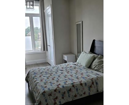 A bedroom with a bed, nightstand, and window.