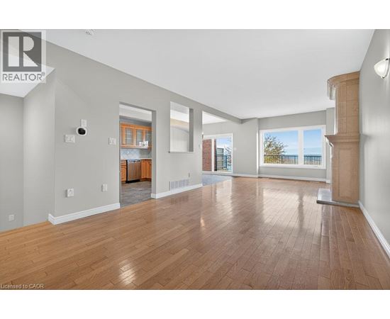 A spacious room with wooden flooring and a large window.