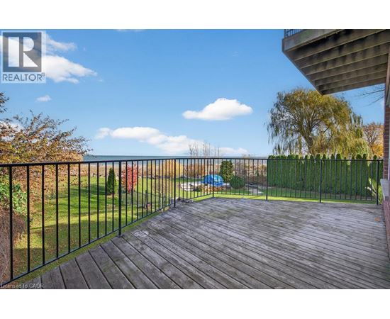 A wooden deck with a black railing overlooks a grassy area.
