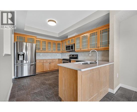 A kitchen with wooden cabinets and a stainless steel refrigerator.