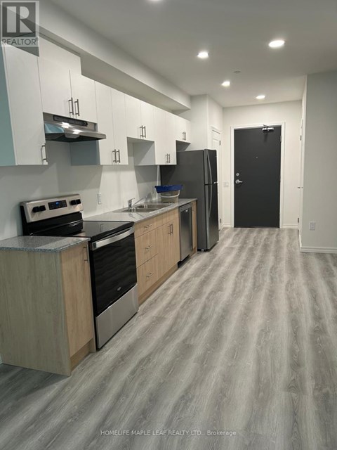 A kitchen with a stove top oven, refrigerator, and cabinets.