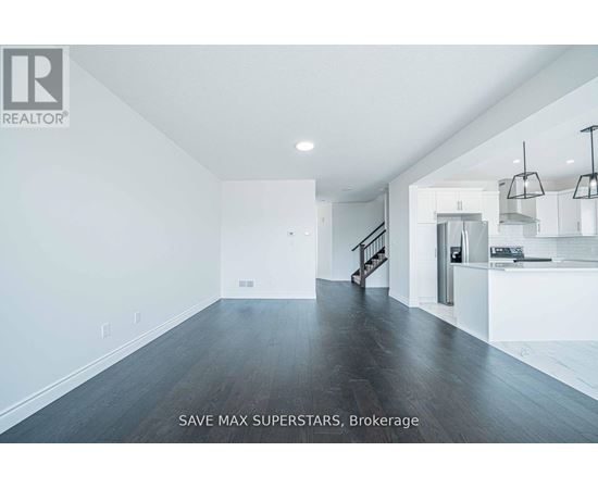A spacious room with a staircase leading to the second floor.