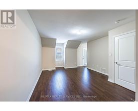A spacious room with wooden floors and white walls.