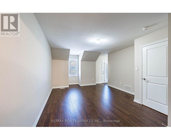 A spacious room with wooden floors and white walls.