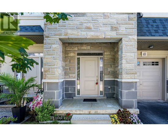 A stone building with a white door and a sign that says RE/MAX Realty Services Inc.
