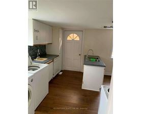 A kitchen with white cabinets and a wooden floor.