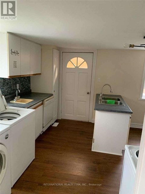 A kitchen with white cabinets and a wooden floor.