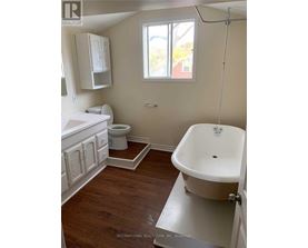 A white bathroom with wood floors and a claw foot tub.