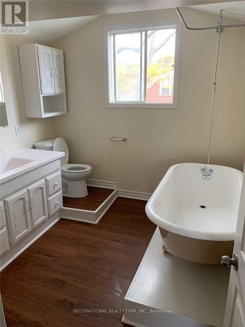 A white bathroom with wood floors and a claw foot tub.
