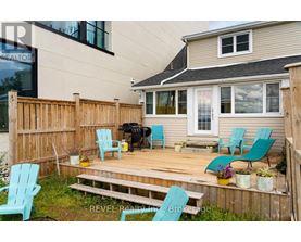 A deck with blue chairs and a grill is in front of a house.