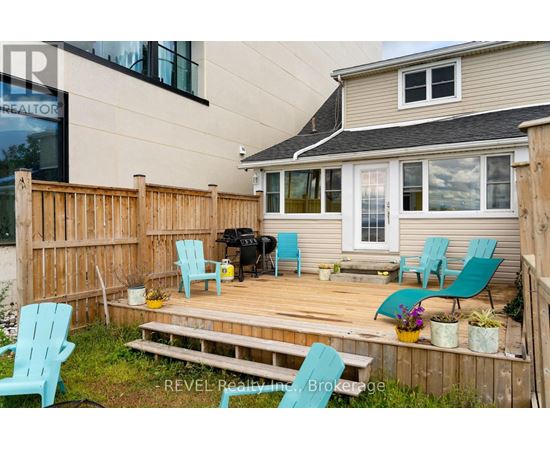 A deck with blue chairs and a grill is in front of a house.