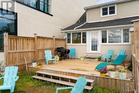 A deck with blue chairs and a grill is in front of a house.