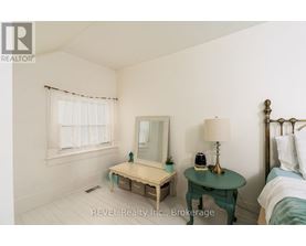 A bedroom with a bed, nightstand, and a small table with a lamp and a phone on it.