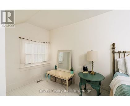 A bedroom with a bed, nightstand, and a small table with a lamp and a phone on it.