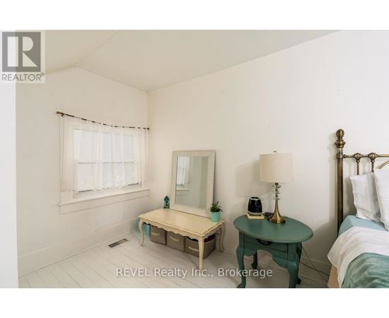 A bedroom with a bed, nightstand, and a small table with a lamp and a phone on it.