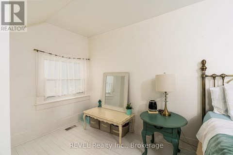 A bedroom with a bed, nightstand, and a small table with a lamp and a phone on it.