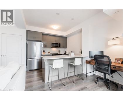 A modern kitchen with white chairs and a black office chair.