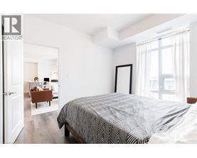 A bedroom with a large bed and a view of a living room through the open door.