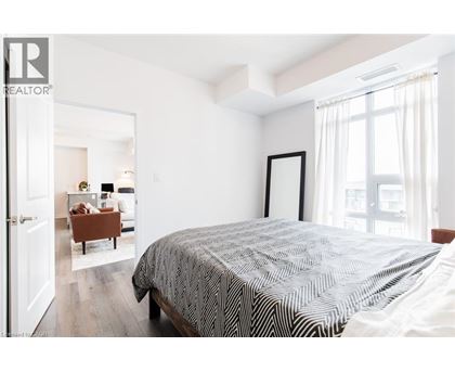 A bedroom with a large bed and a view of a living room through the open door.