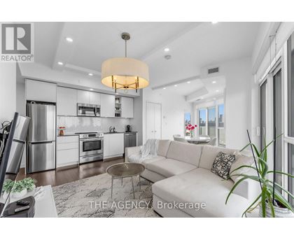 A modern kitchen with a white color scheme and a dining area with a white couch.