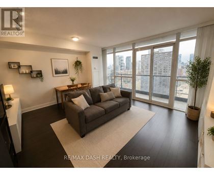 A living room with a grey couch and a large window.