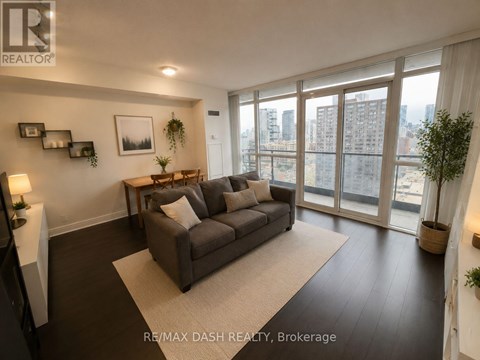 A living room with a grey couch and a large window.