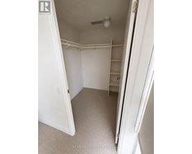 A white bedroom with a door open to a hallway.